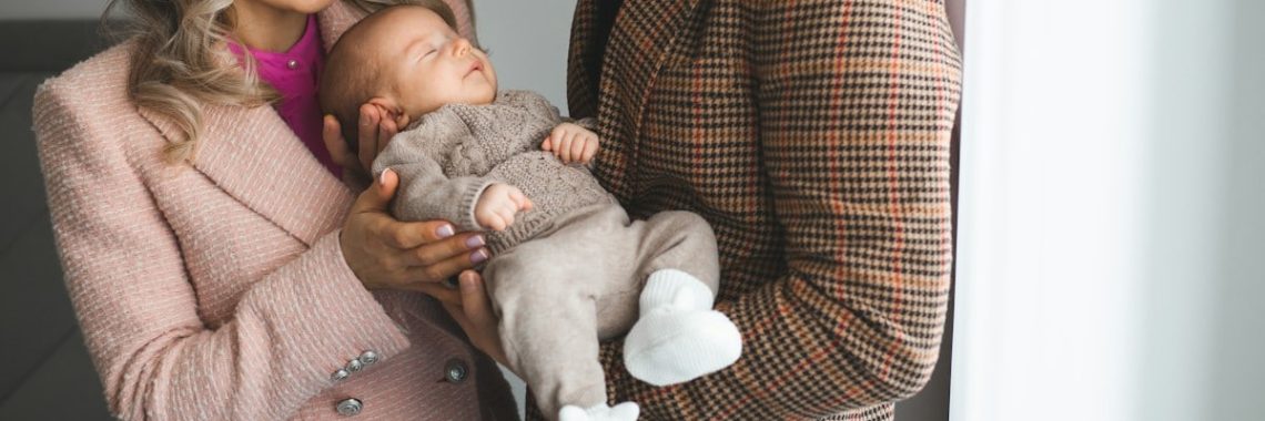 Mother and father holding their young baby boy in their hands.